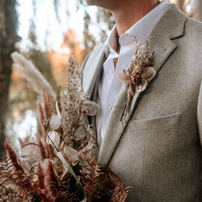 The groom holds a pampas grass bouquet