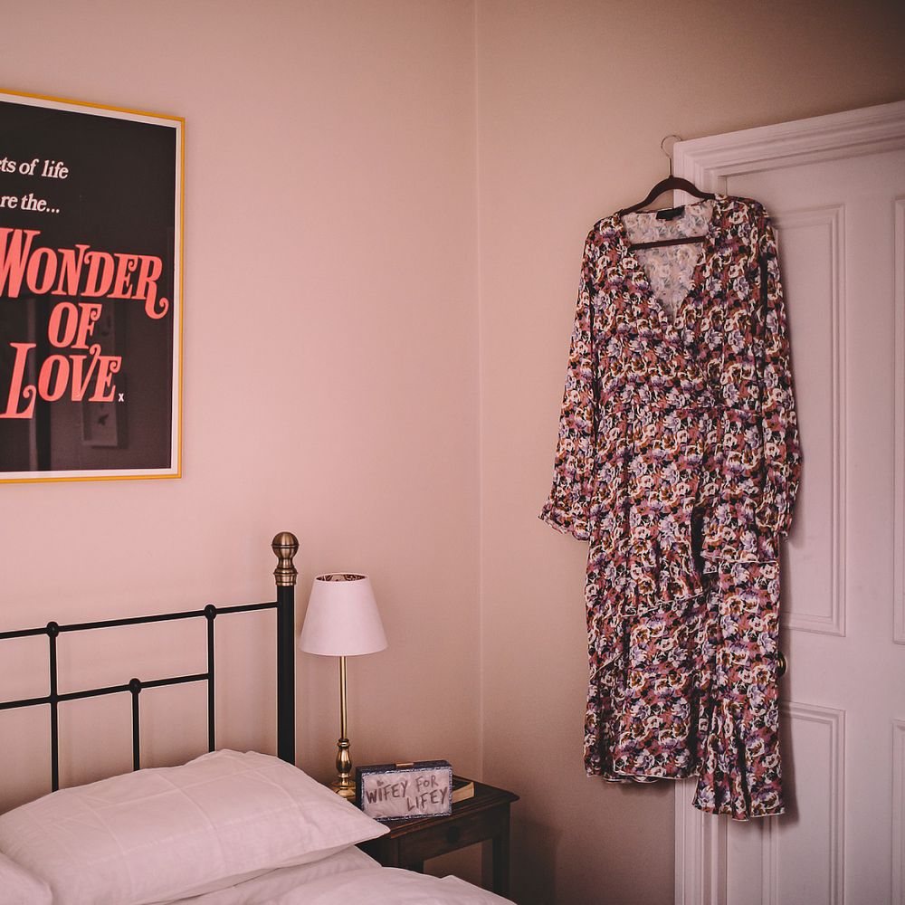Brides floral gown hands beside bed on her wedding day