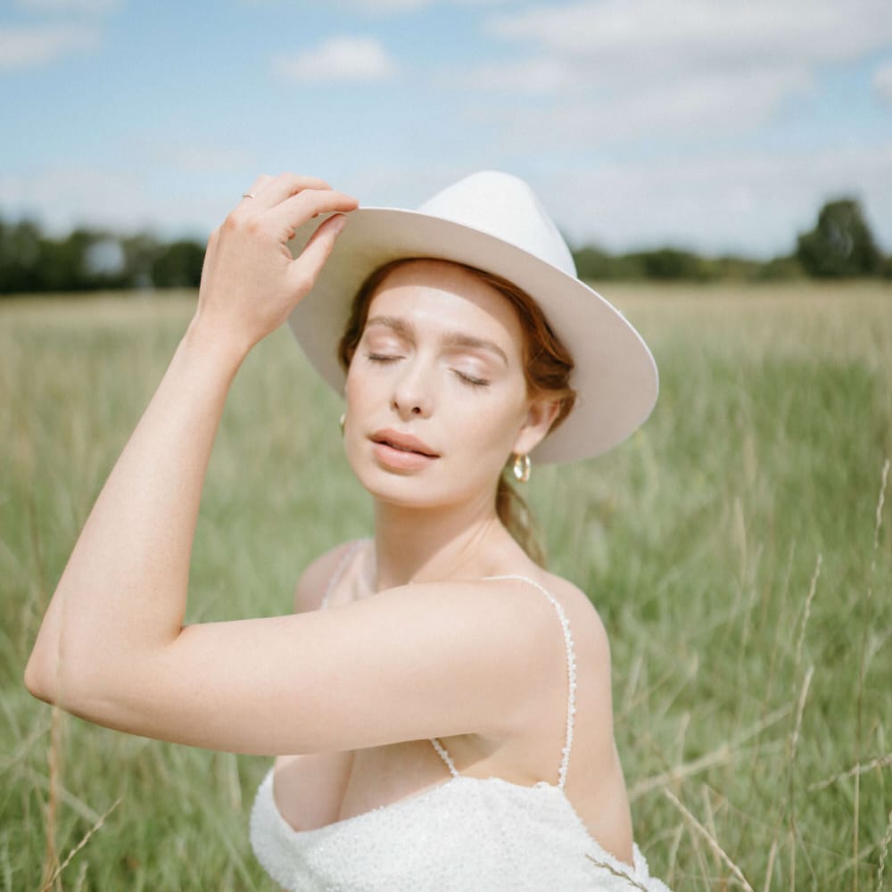 Bride in the fields at Berwick Lodge wearing a bridal stetson hat