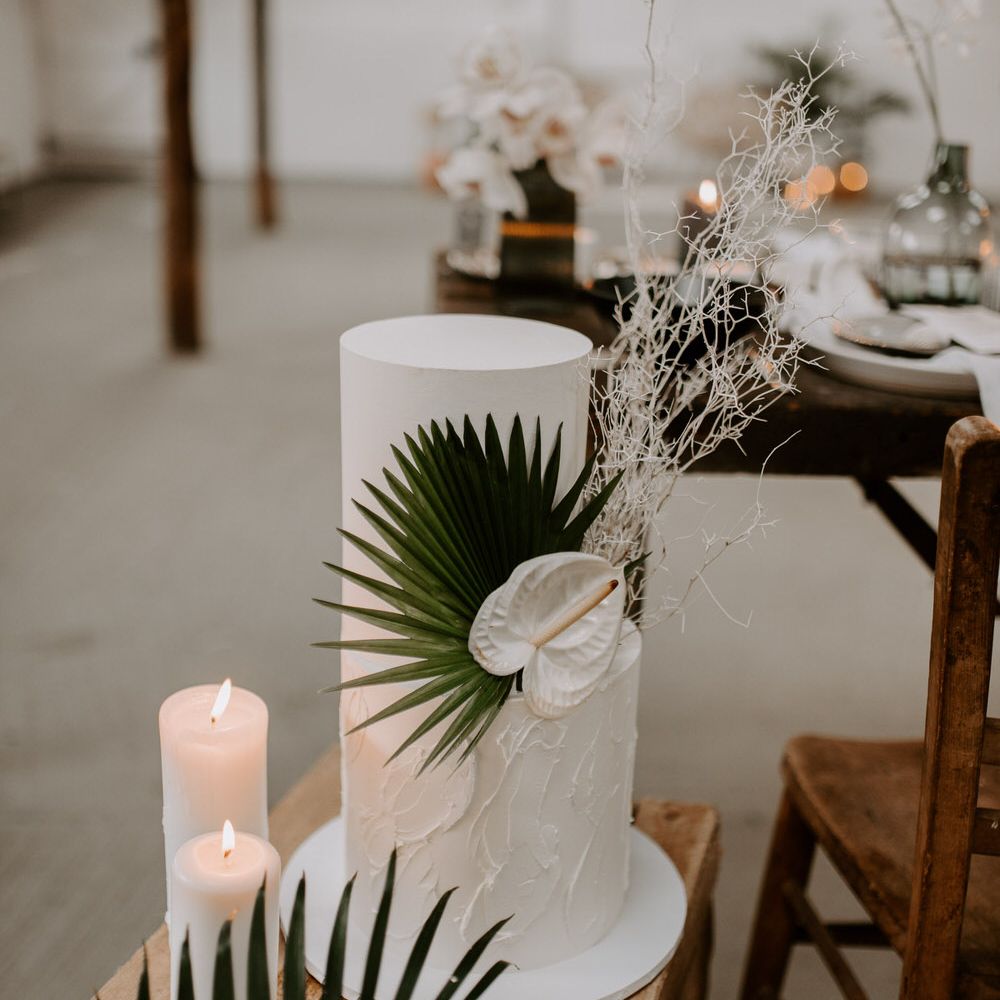 Two tier white wedding cake with palm leaf and white anthurium flower decoration