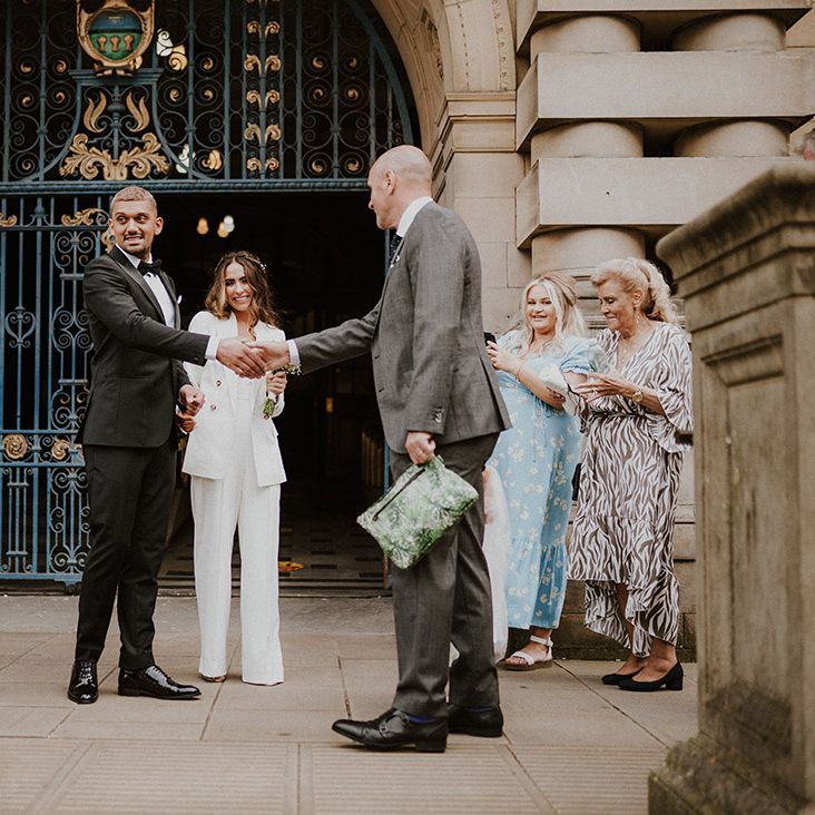 Groom shaking hands with guest outside his Sheffield registry office wedding 