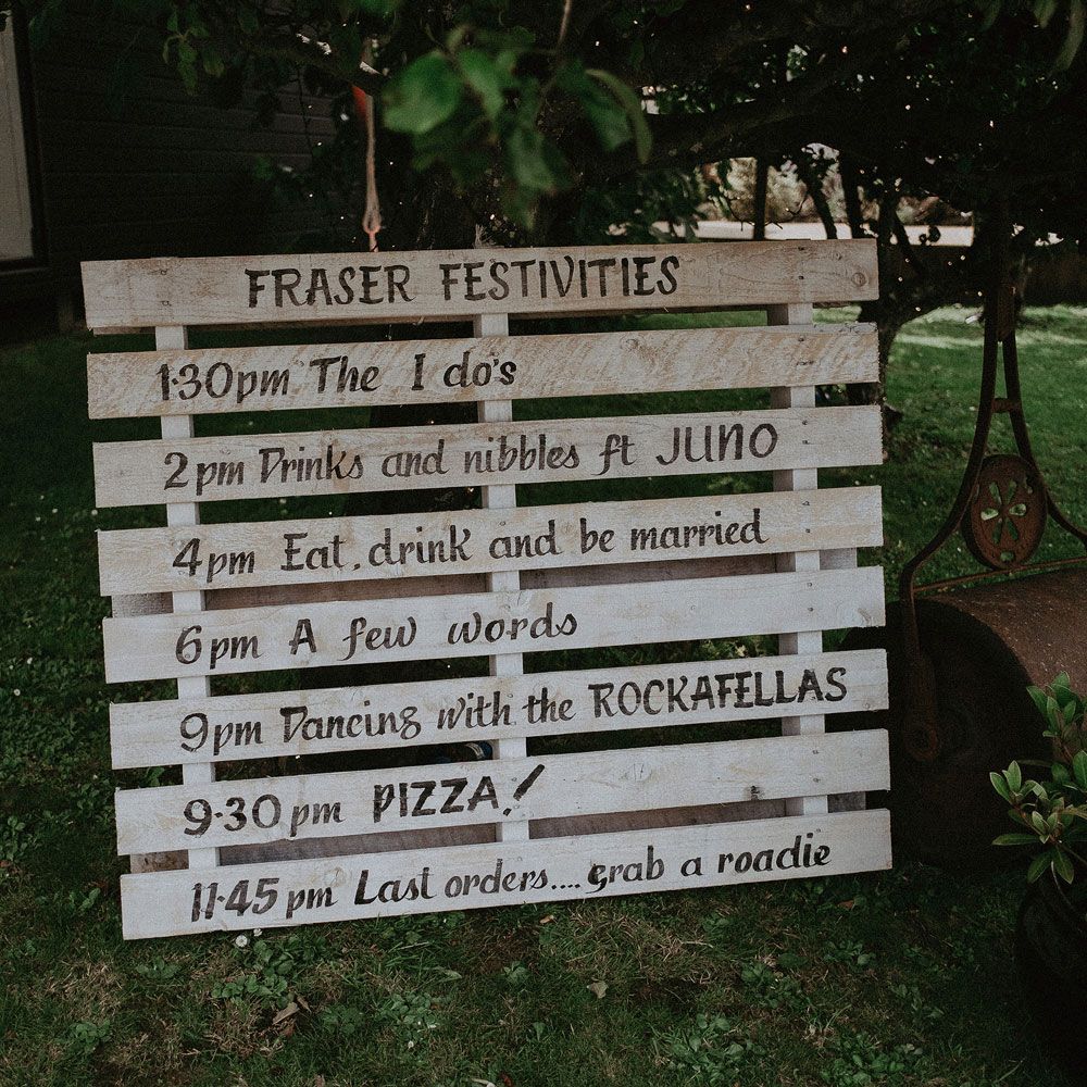 White wooden pallet wedding order of the day sign outside at Idle of Wight wedding with macrame wedding decor