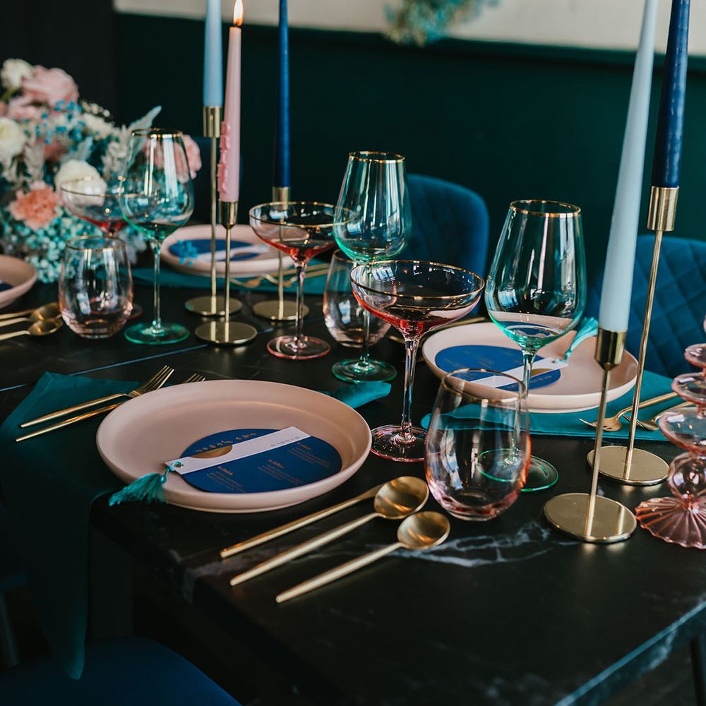 Pink and teal wedding table decor with coloured plates, glassware and flowers 