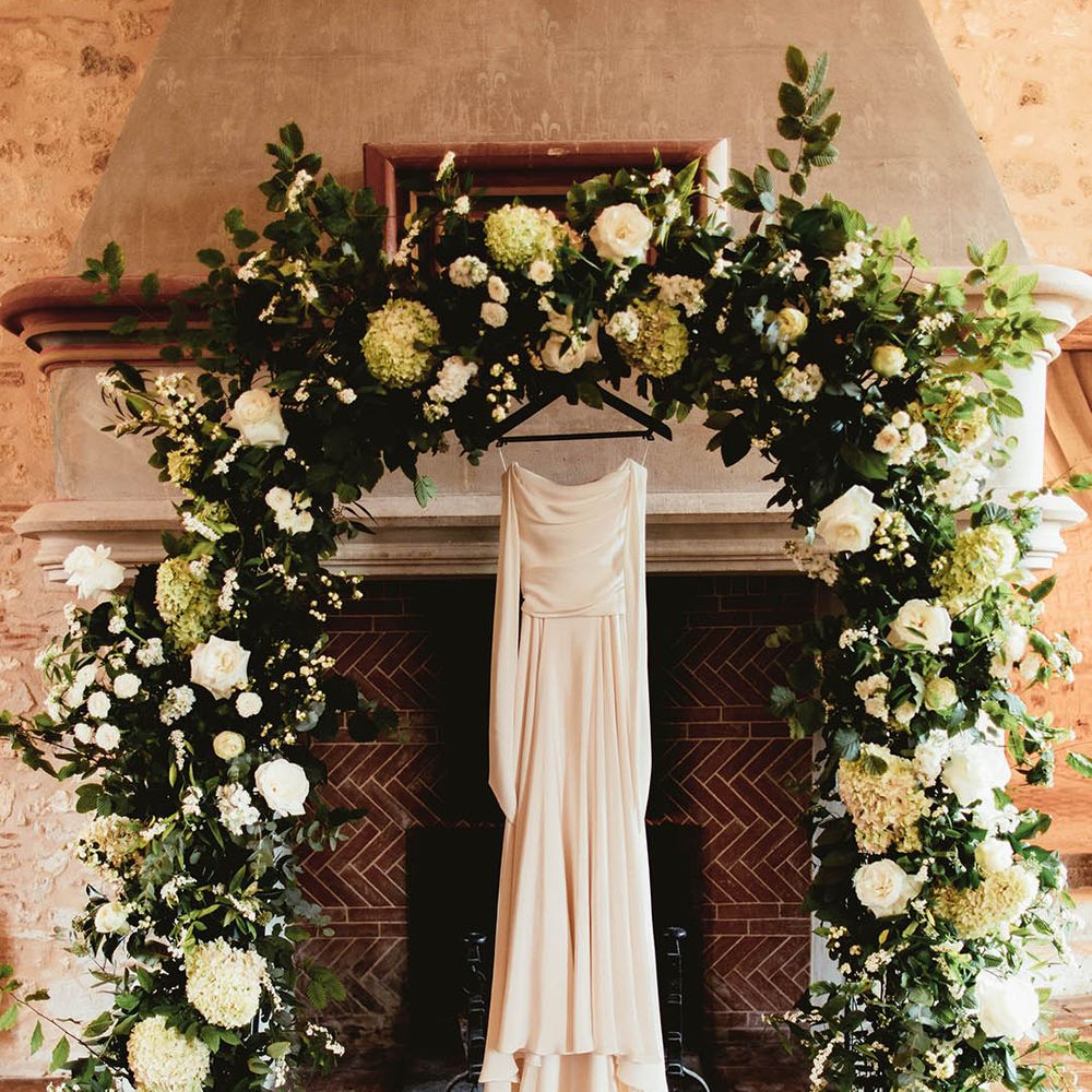 Bridal gown hands between floral archway complete with white florals