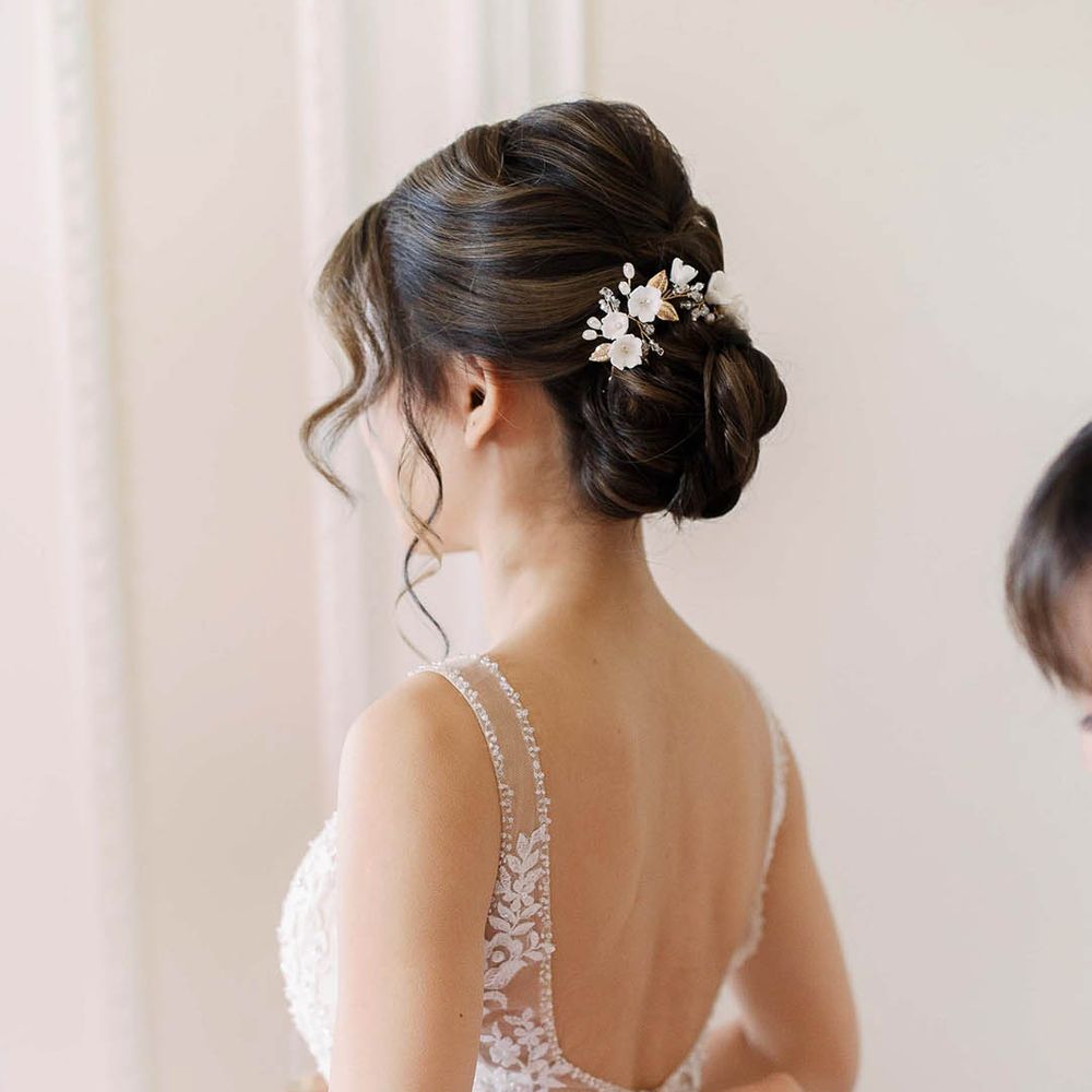 Bride has her dress done up on the morning of her wedding day and wears her black hair in a low bun
