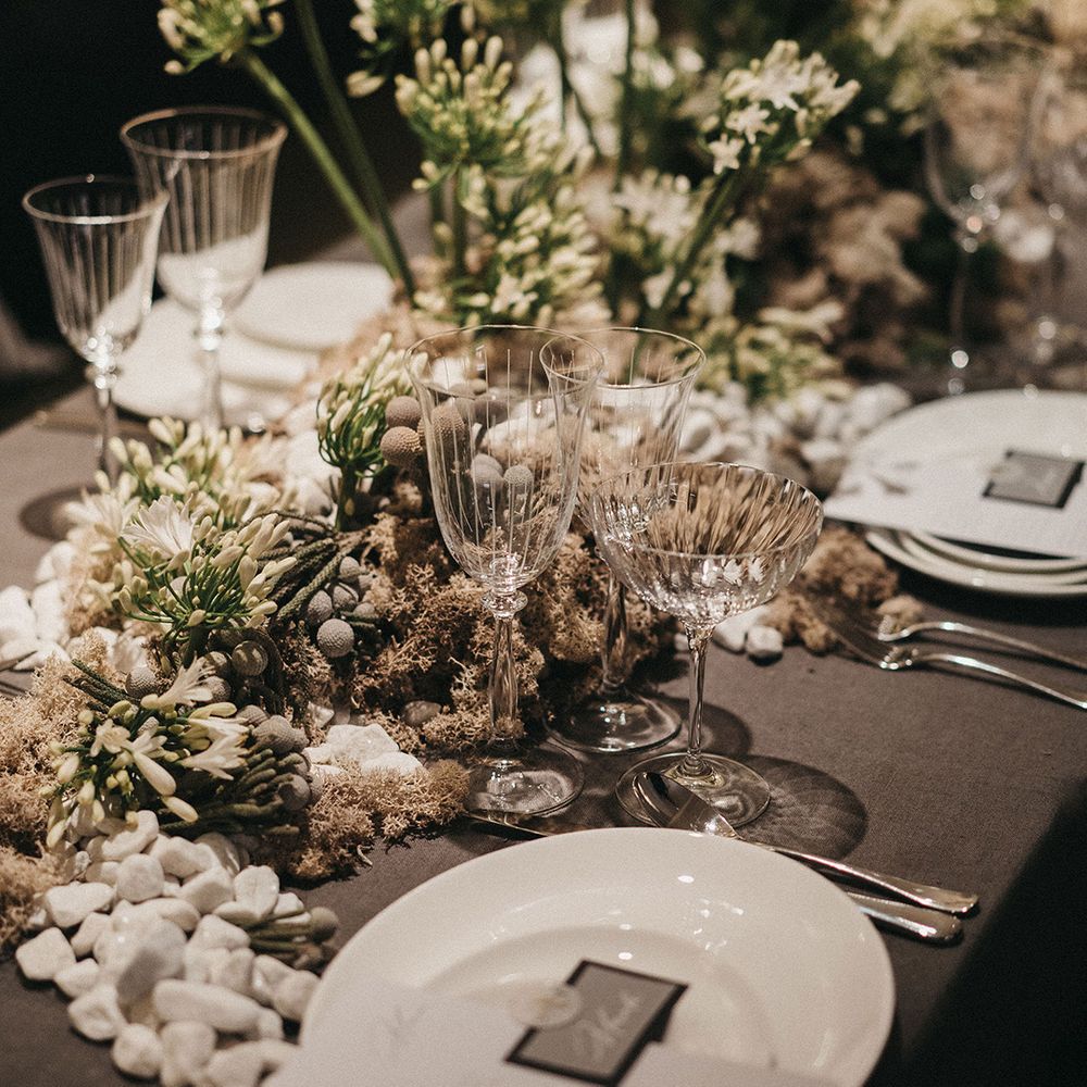 elegant wedding table decor with white and green floral centrepieces and glass goblets and saucers 