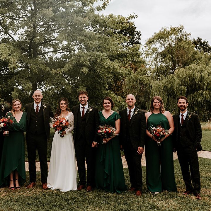 Wedding party with bridesmaids in emerald green dresses and groom and groomsmen in green wool suit and bride in illusion lace top long sleeve dress 