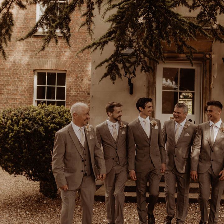 Groom with his groomsmen in matching neutral wedding suits for boho luxe wedding 