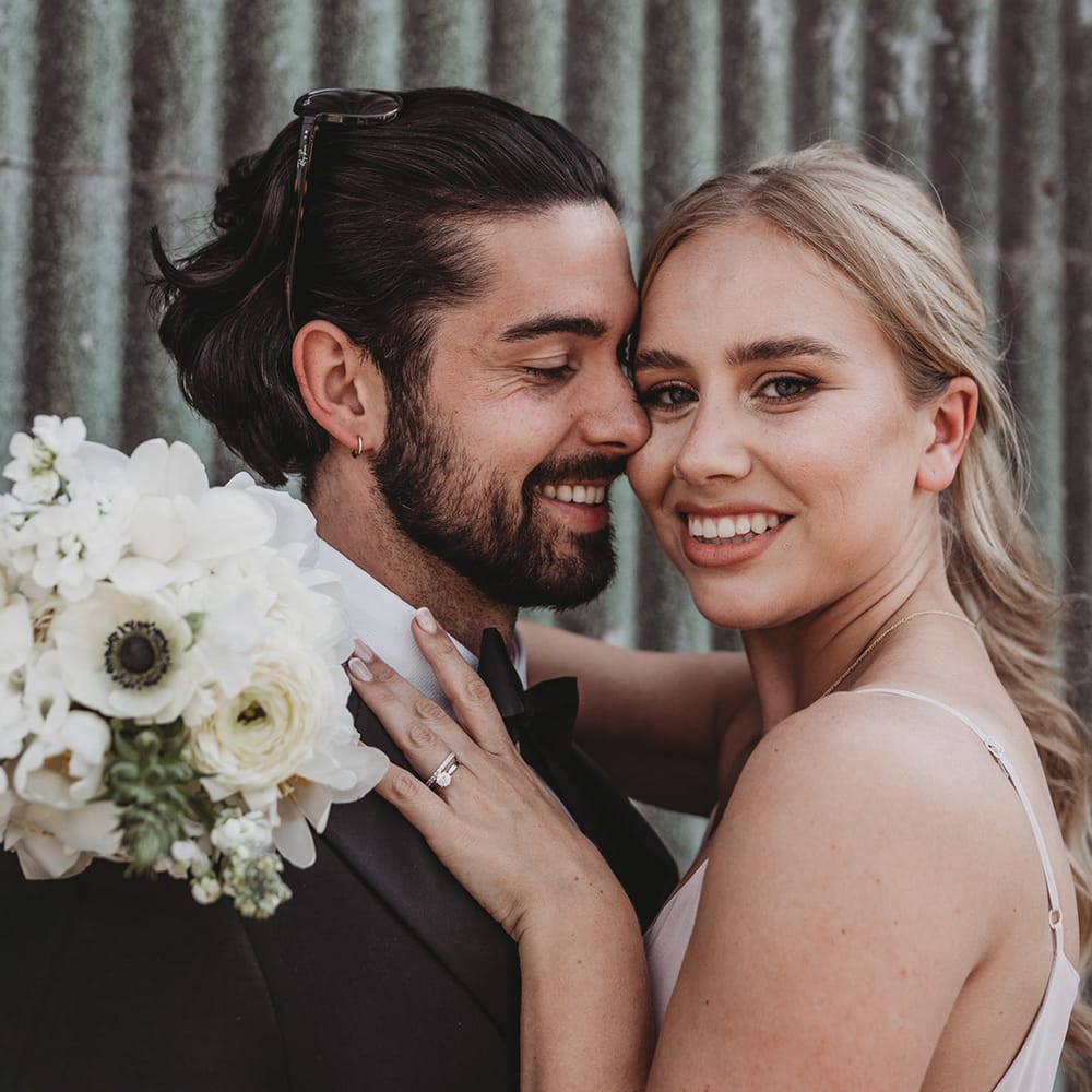 Bridesmaid hugs a groomsman in black tie and sunglasses 