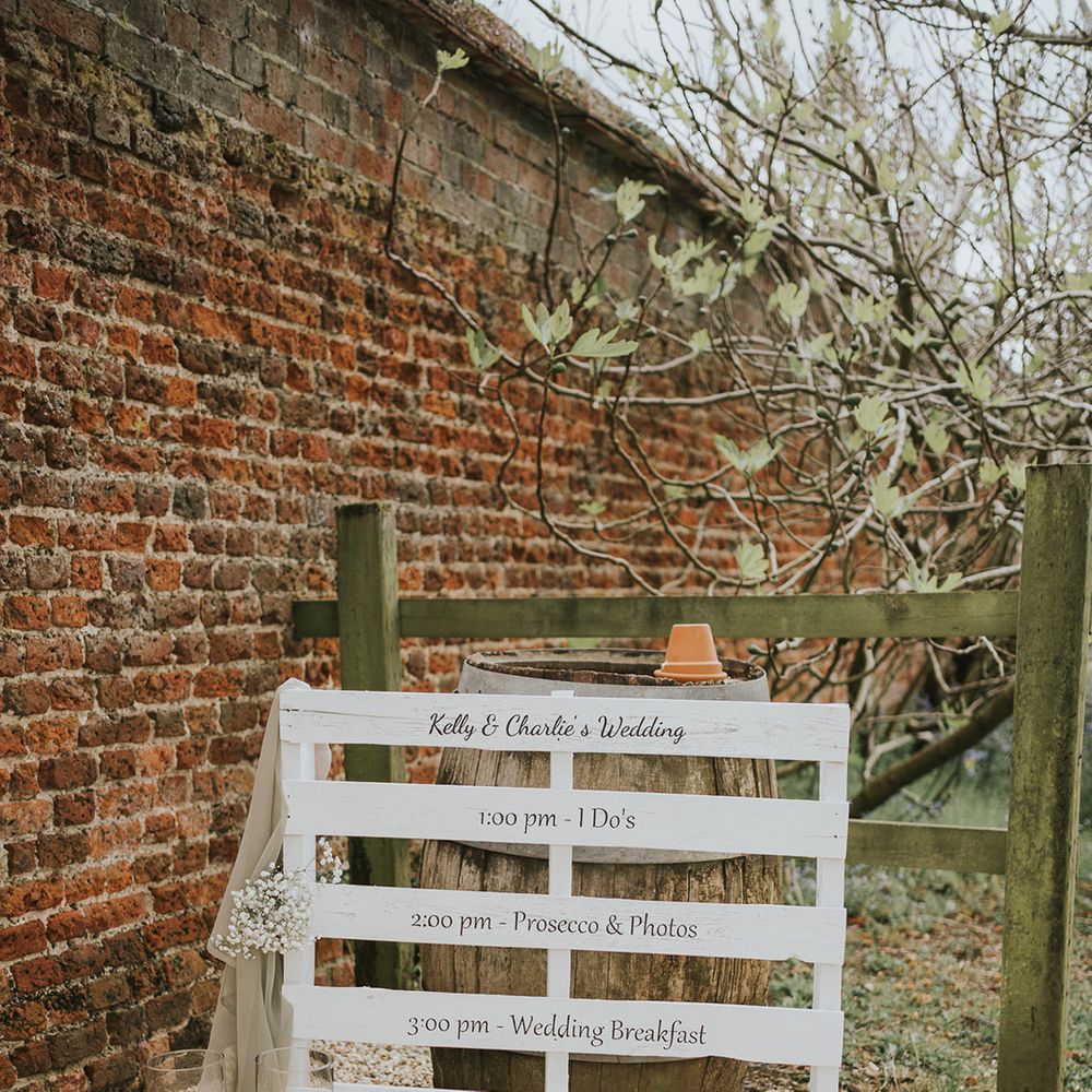 White wooden pallet order of the day wedding sign with gypsophila and pillar candles 