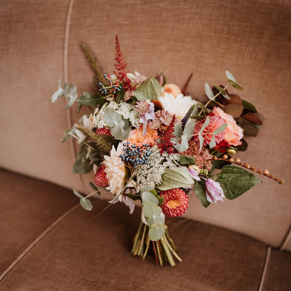 Wedding bouquet with white and pink carnations, garden roses, red strawflower, eucalyptus, baby’s breath and various dried flowers 
