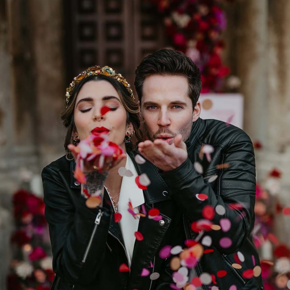 Bride and groom in black personalised leather jackets doing colourful confetti throw at disco themed wedding