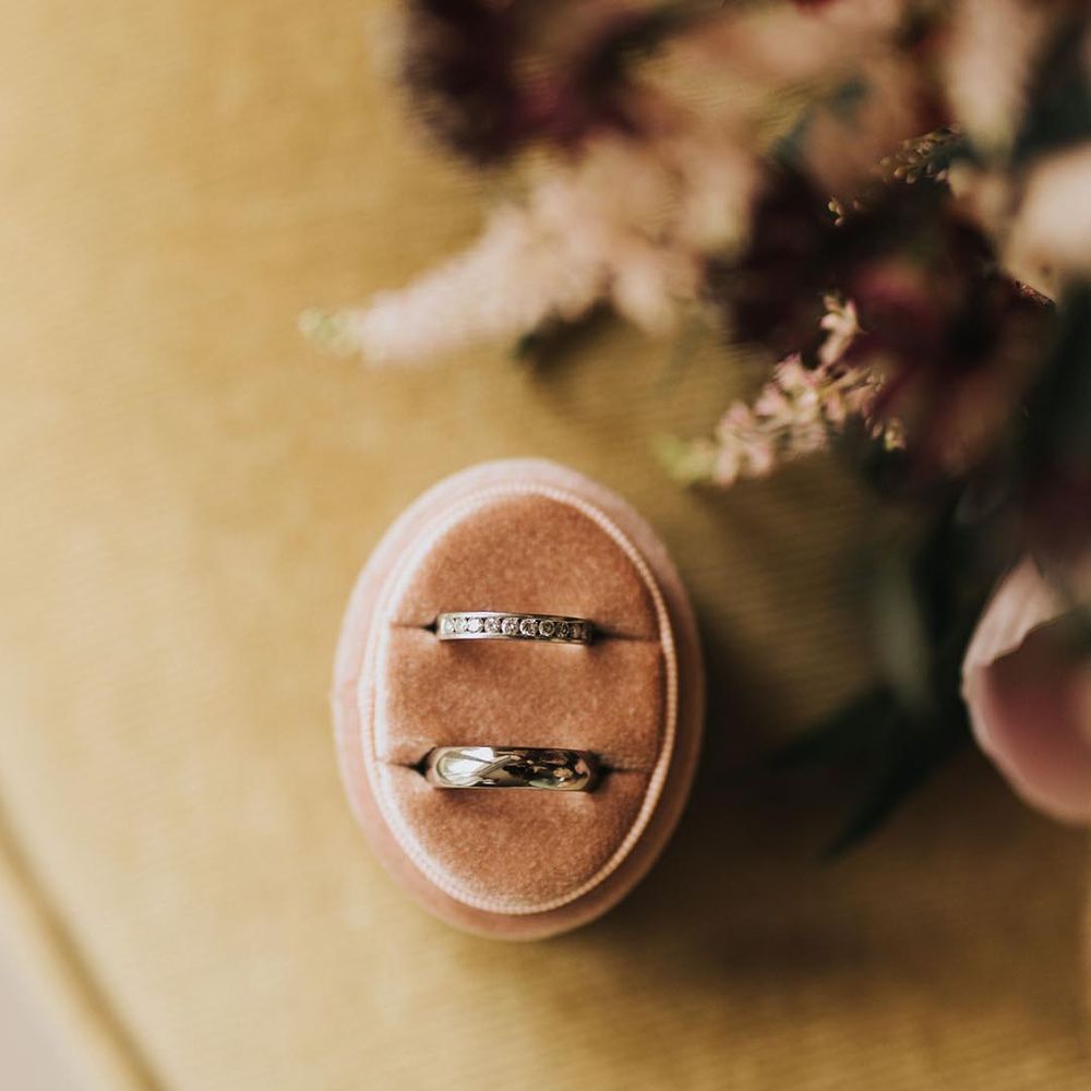 Oval pink velvet ring box with a thick plain silver wedding band with a diamond wedding band for the bride and groom