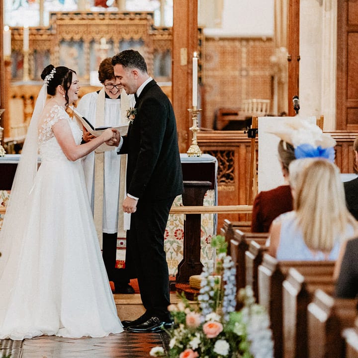 The bride and groom laugh together at their traditional church wedding with pastel wildflower decor 