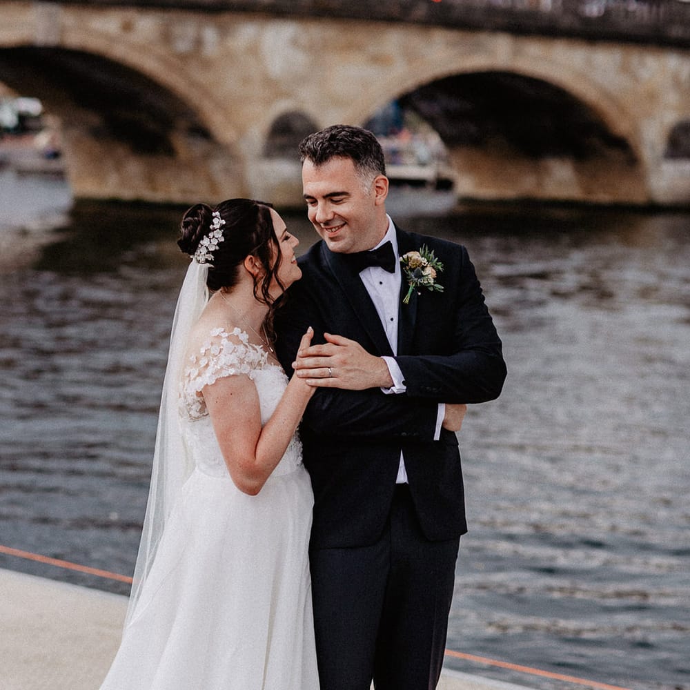 Bride in flower Suzanne Neville wedding dress with custom flower hairpiece smiling with the groom in black tie at Culden Faw Estate 