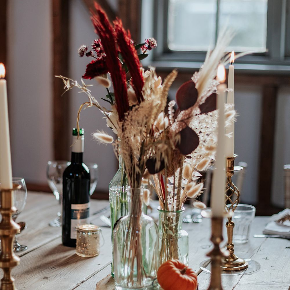 Dried wedding grass and flowers in glass vase with mini pumpkin decor for boho autumnal wedding at Milling Barn