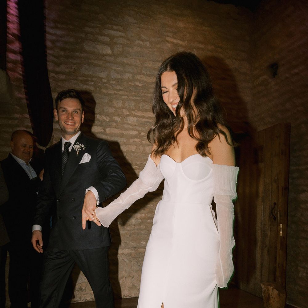 Bride wearing platform Jimmy Choo pearl shoes with matching pearl detachable sleeves with the groom in dark blue suit 
