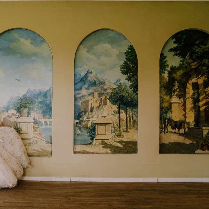 Bride in v-neck long sleeve shoulder cut out 3d appliqué wedding dress with flecks of gold twirling around by the hand painted murals at Braxted Park wedding venue 