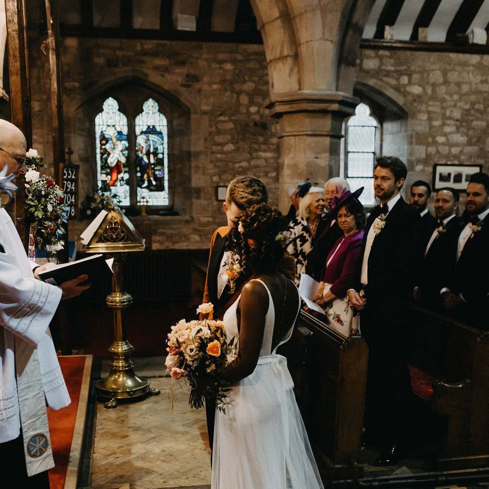 Bride standing with groom at alter wearing v neck sleeveless wedding dress with 3D floral applique train 