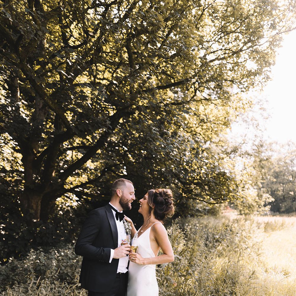 Bride in satin slip wedding dress kissing the groom for couple portrait as the sun starts to set