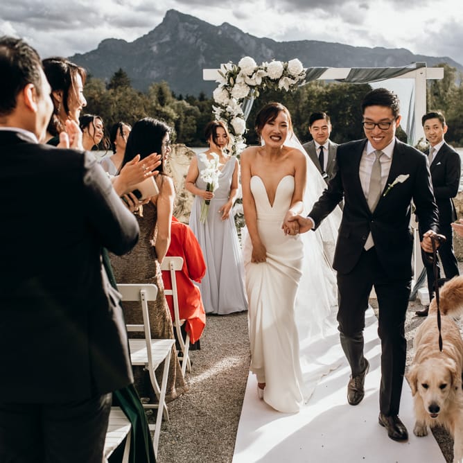 Bride and groom descending down the aisle with their pet dog 