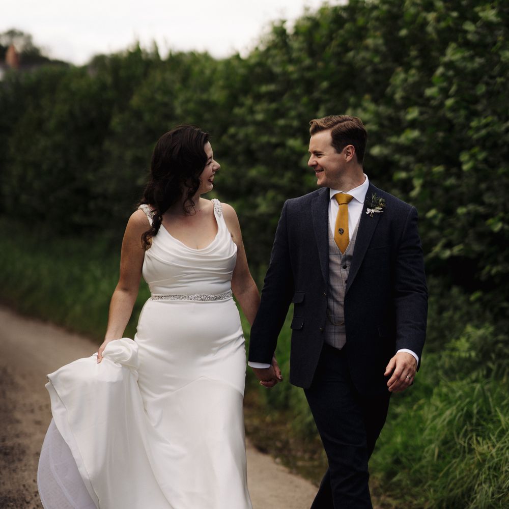 Bride & groom walk together in the countryside 