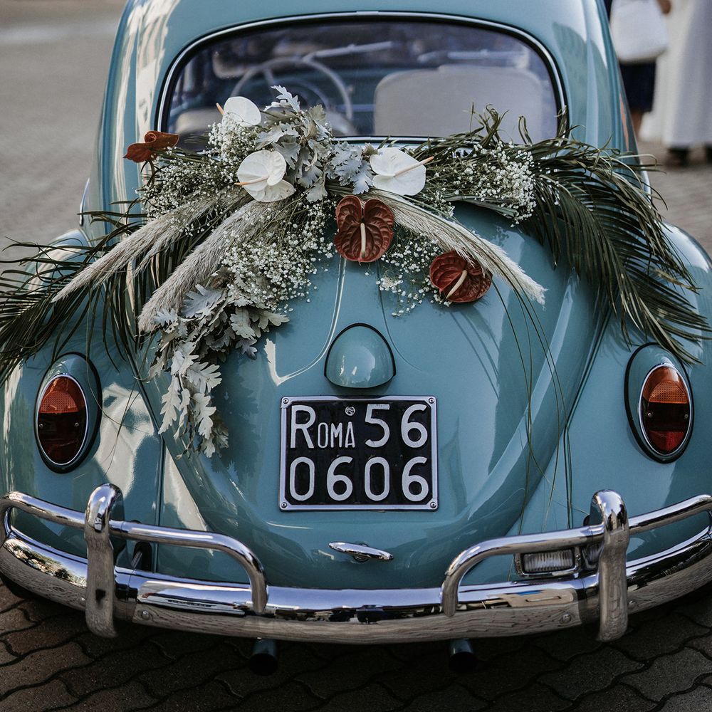 Blue Volkswagen Beetle with dried flower arrangement decorating the back 