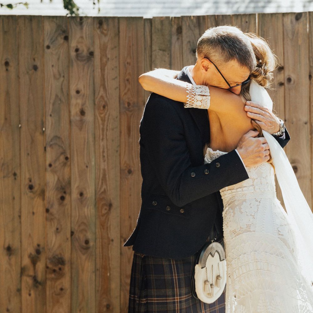 Father-of-the-bride in kilt hugs boho bride in Rue De Seine dress