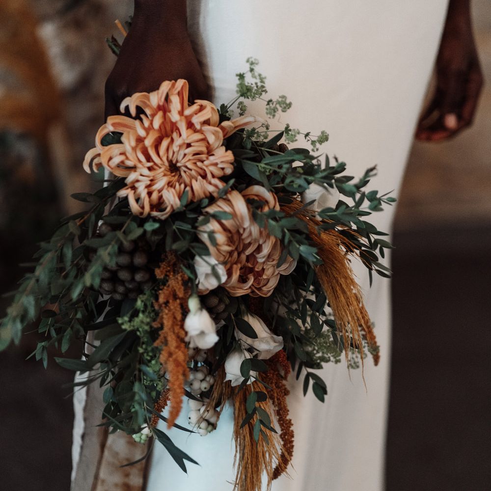 Orange and green wedding bouquet with flowers, foliage and dried grasses 