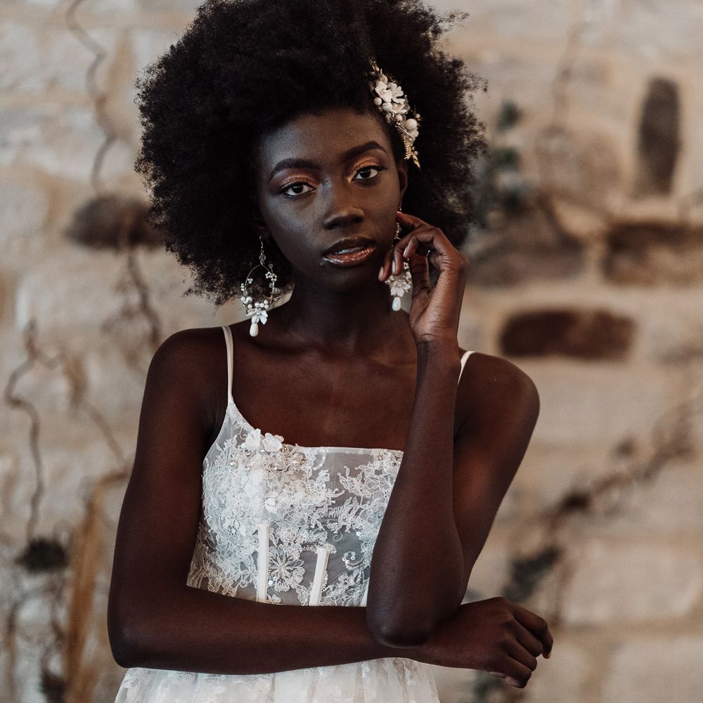 Black bride with afro hair with hoop earrings and hair slide with shimmering eye shadow and lip gloss makeup 