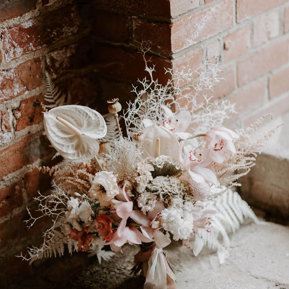 Tropical wedding bouquet with pink and white flowers including chrysanthemums, lilies, anthuriums and white ferns