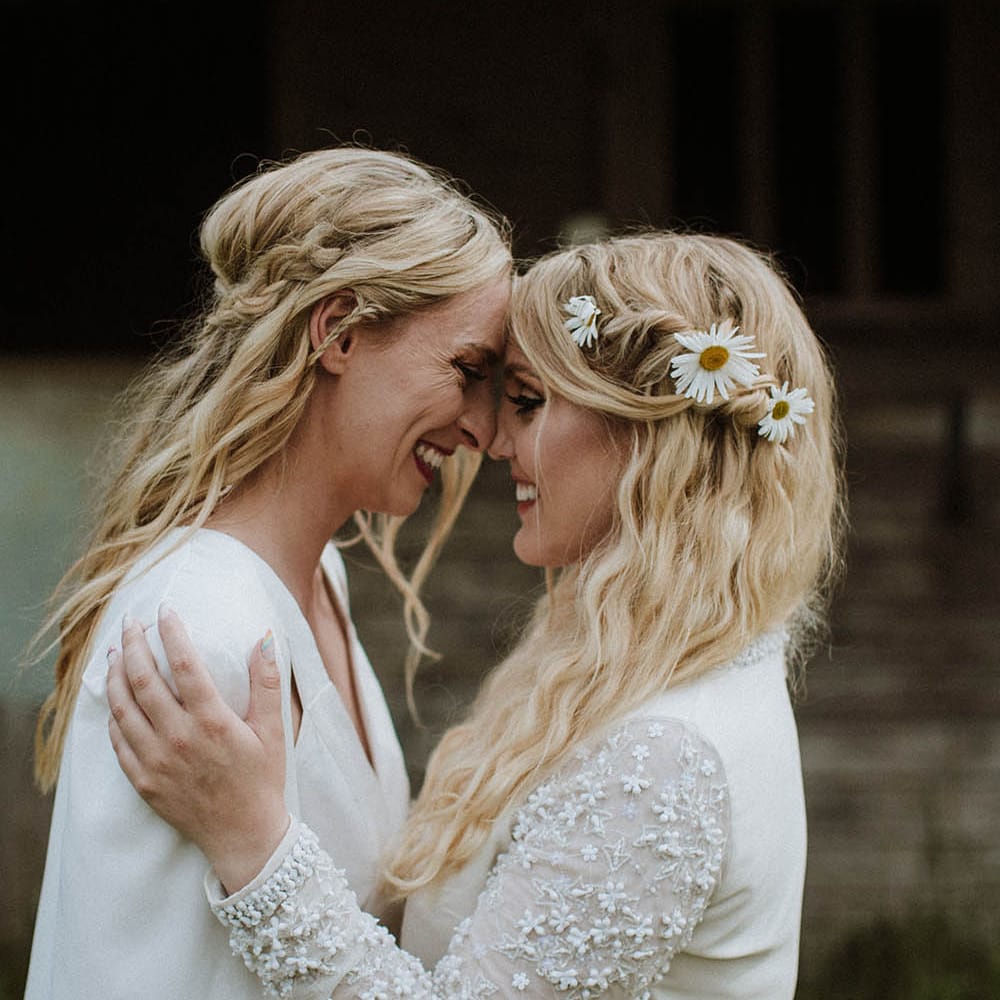 two boho brides with long wavy hair decorated with braids and fresh flowers