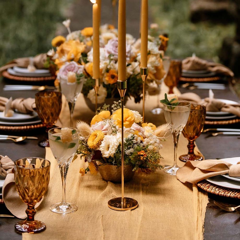 Wedding table decor with yellow table runner, gold candles sticks and yellow taper candles and floral arrangements 