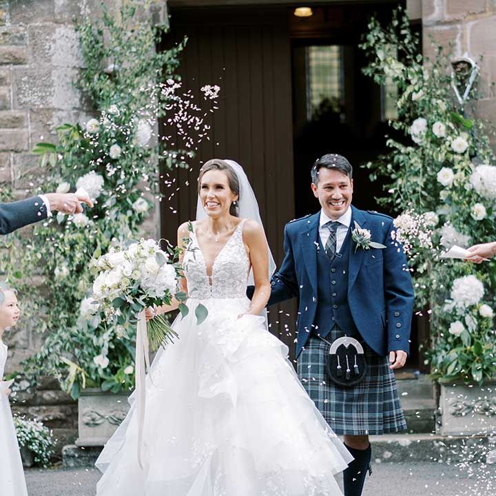 Confetti moment with bride in a princess wedding dress and groom in a tartan kilt 