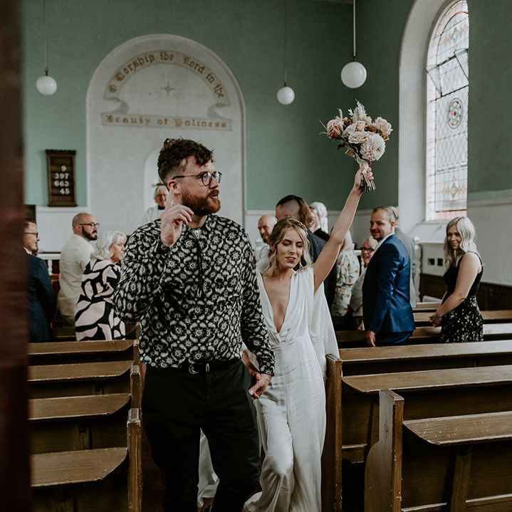 Bride & groom celebrate as they walk down the aisle with one another