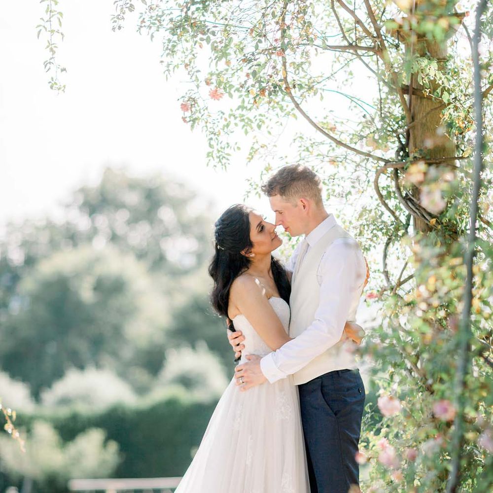 Bride & groom look lovingly at one another outdoors as they embrace on their wedding day