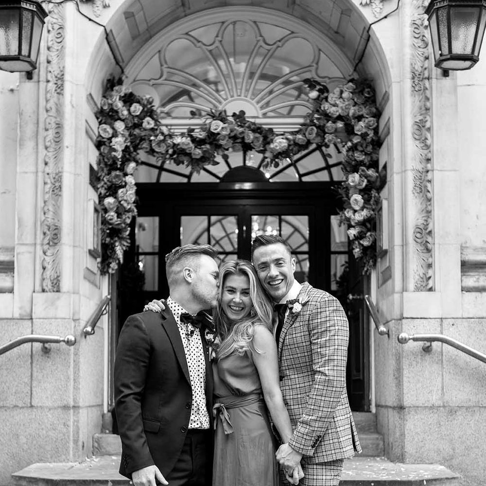 Grooms stand with wedding guest on their wedding day
