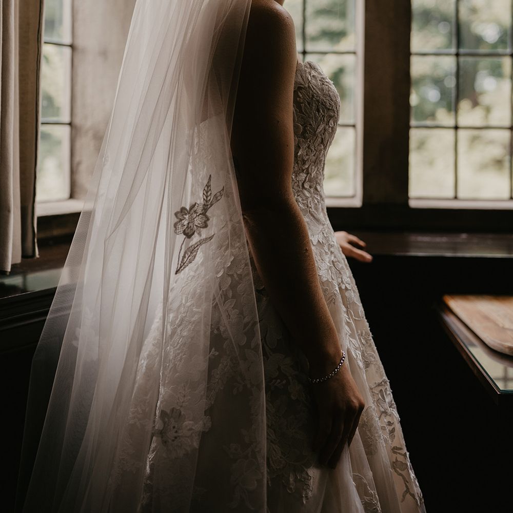 Bride in lace sweetheart wedding dress with lace detail and veil with similar lace detailing 
