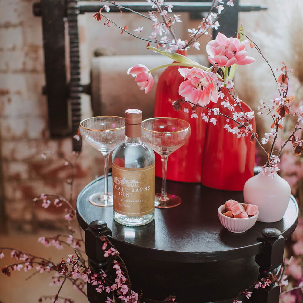 Side table with two coupe champagne glasses, cherry blossom and flower stems in vases 