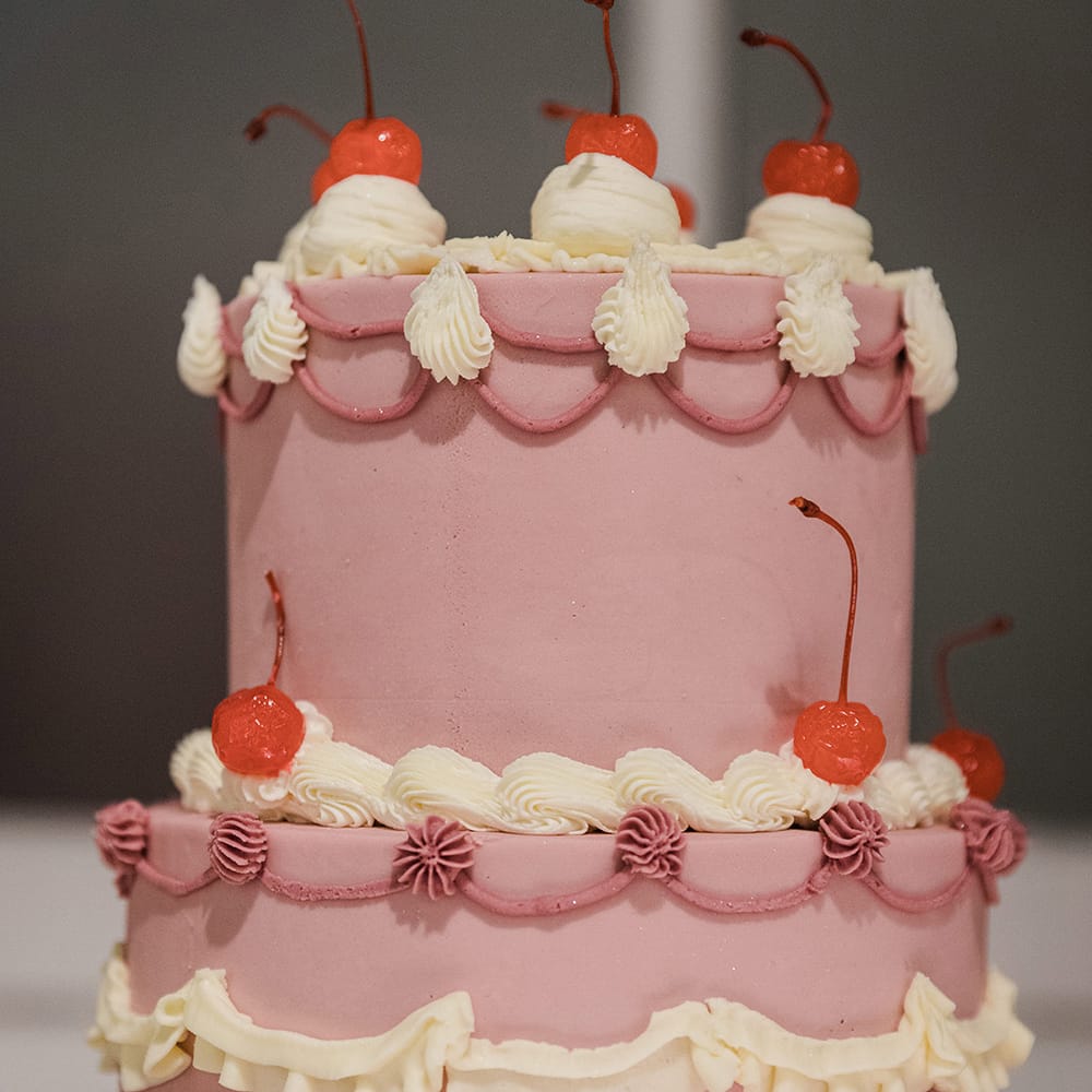 Close up of the three tier purple and white wedding cake with decorative icing and cherries