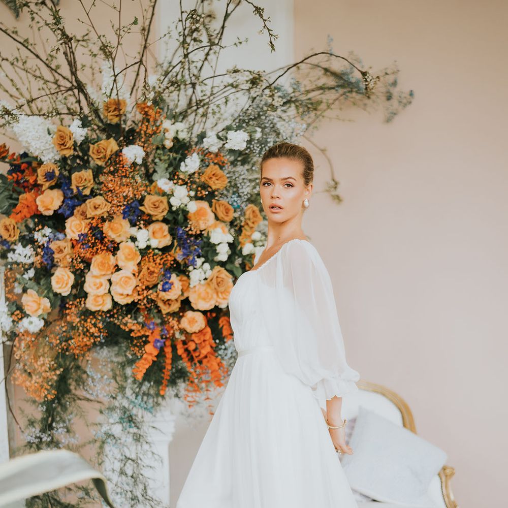 Bride with sleek hair in a bun with pearl earrings in a white wedding dress with sheer balloon sleeves 
