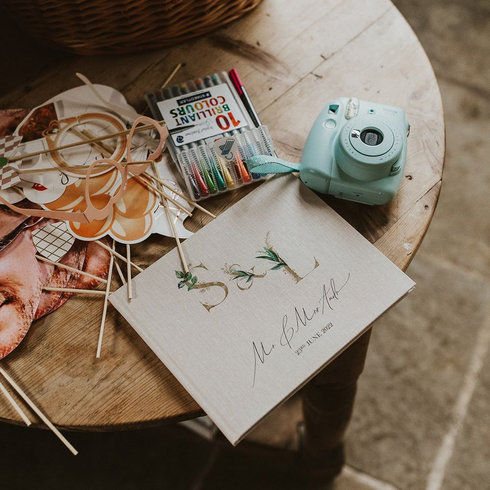 Personalised wedding guest book with coloured pens, a polaroid camera and props 