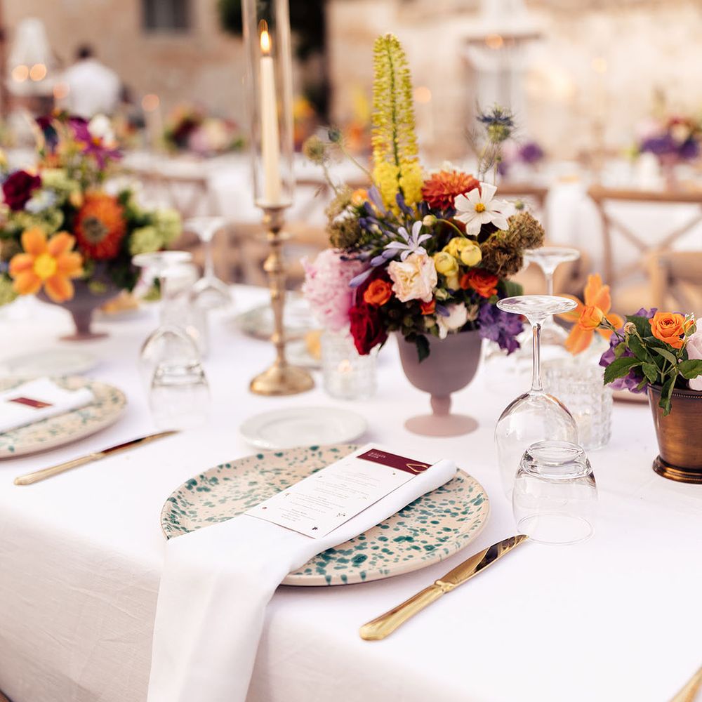 Speckled white and green plates with small colourful flower arrangement and gold cutlery