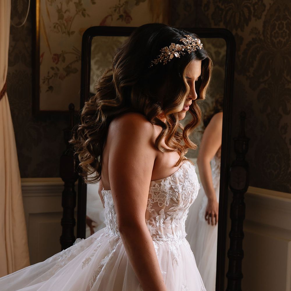 Bride in a strapless corset wedding dress with tulle skirt wearing a gold crown with flowers 