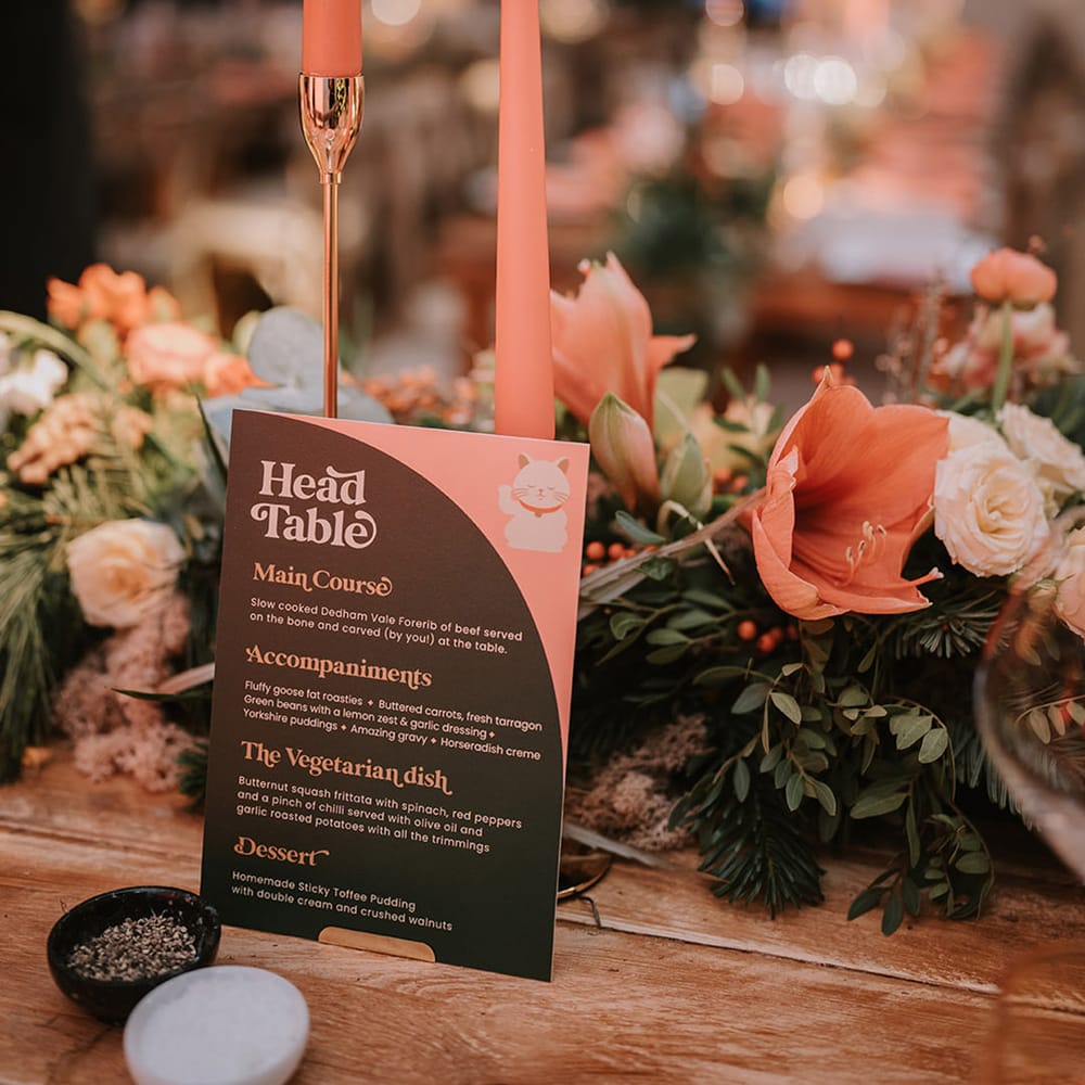 Head table wedding menu, orange tapered candles in gold candlestick holders with orange flower and foliage table runners
