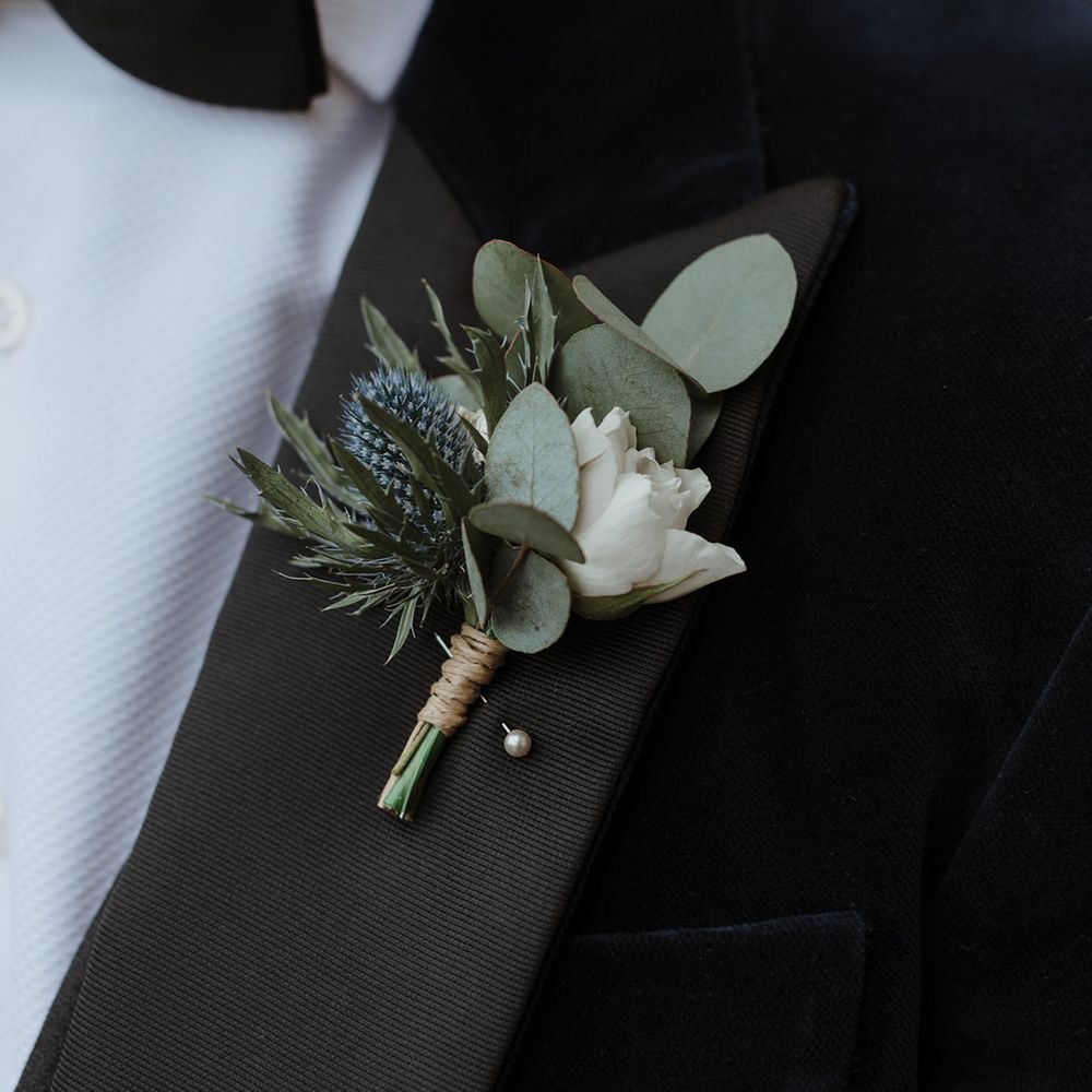 Groom in black tuxedo with traditional white flower buttonhole for wedding 