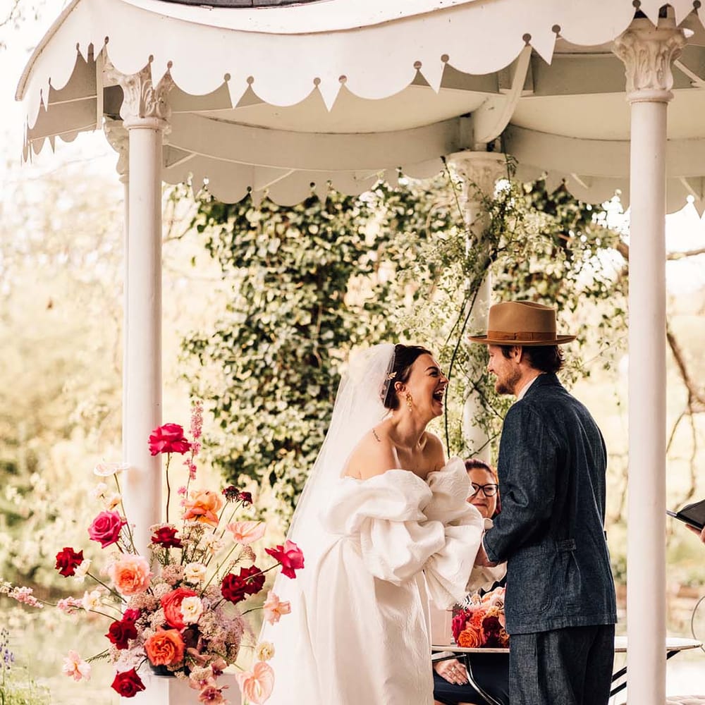 The bride and groom hold hands under the gazebo at Preston Court for their outdoor ceremony 