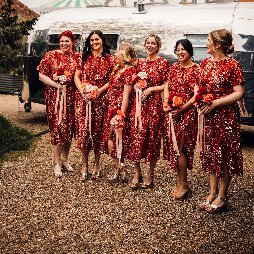 Bridal party in matching red sequin midi bridesmaid dresses in front of silver Photo Booth trailer 