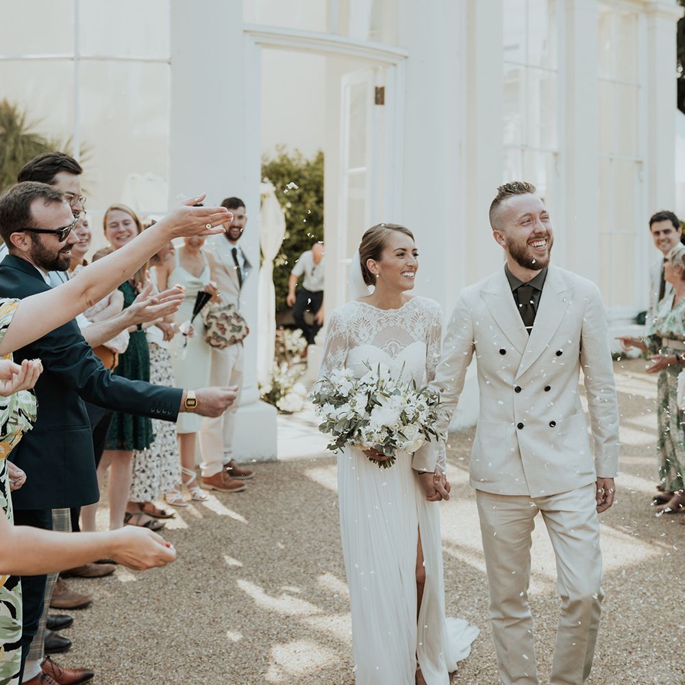 confetti moment outside Gunnersbury wedding venue with beige wedding suit and Catherine Deane wedding dress