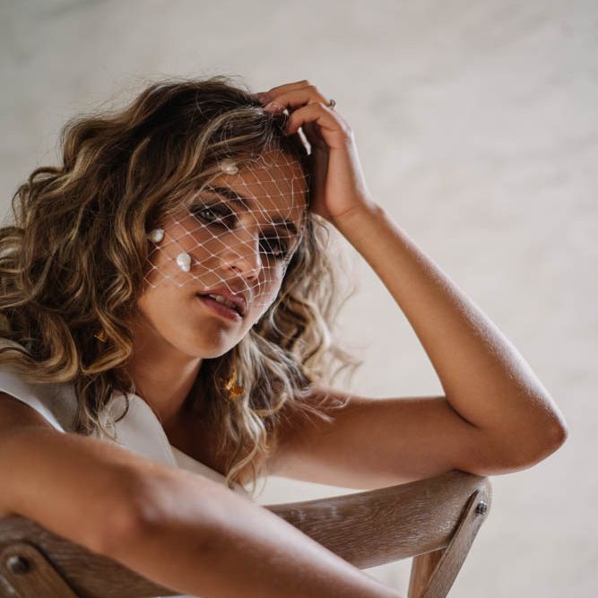 bride with curly hair wearing a birdcage veil